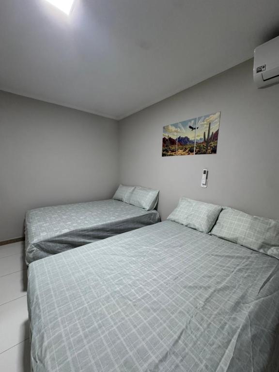 a bedroom with two beds and a painting on the wall at Casa Lanôh in Canindé de São Francisco