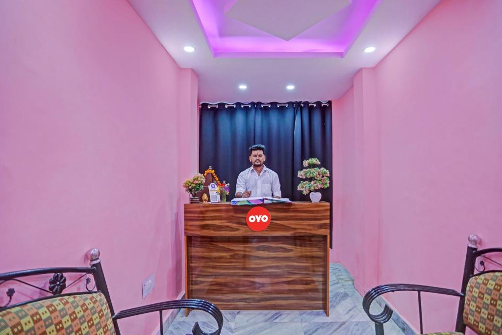 a man standing at a desk in a pink room at Hotel O Sunshine in Kalkaji Devi