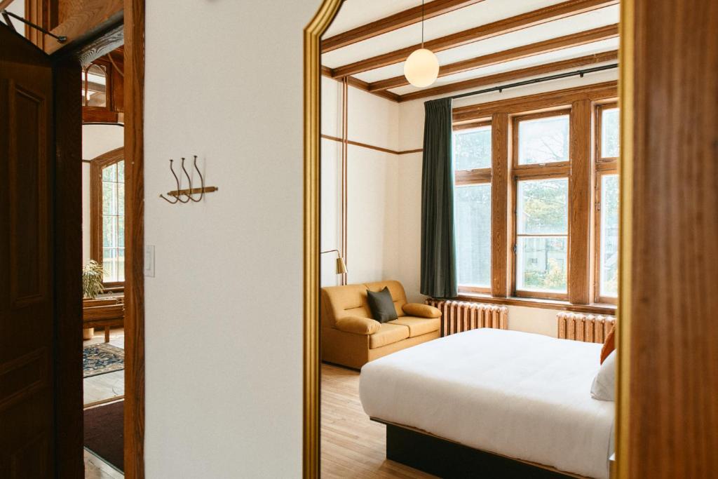 Un dormitorio con una cama y un sofá y una ventana. en Hôtel Château Cran Chaud Chicoutimi, en Saguenay