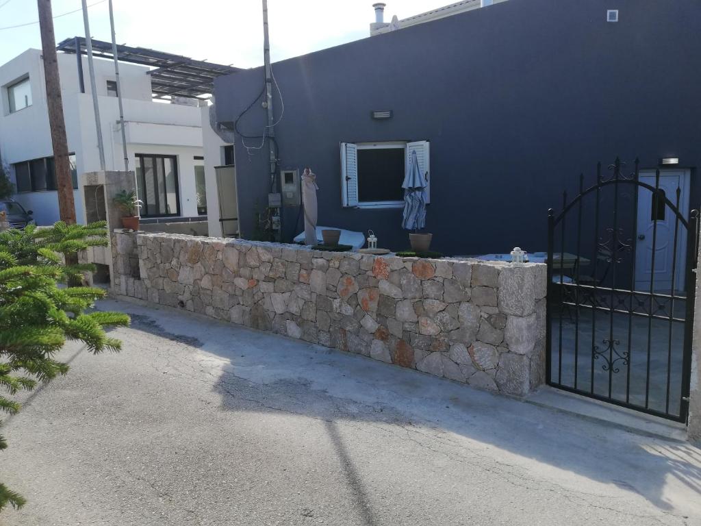 a stone retaining wall next to a building with a gate at SPYROS STONE house in Preveza