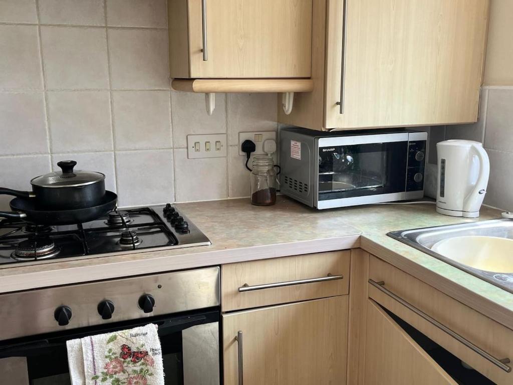 a kitchen with a stove and a microwave at Canal Way- Cozy 3-Bed House in Ilminster