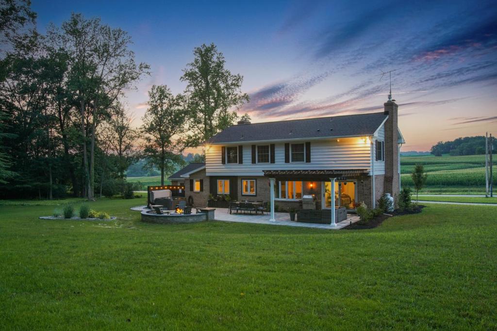a large house with a large yard with a sunset at Zook Manor with Hot tub Firepit and Game Room in Atglen