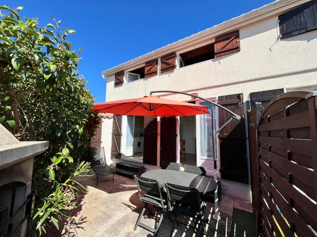 d'une terrasse avec une table et un parasol rouge. dans l'établissement Maison T3 cabine 4 couchages, terrasse cloturée, résidence Sun village avec piscine commune, 300m de la plage à PORTIRAGNES -LRSUNP5, à Portiragnes