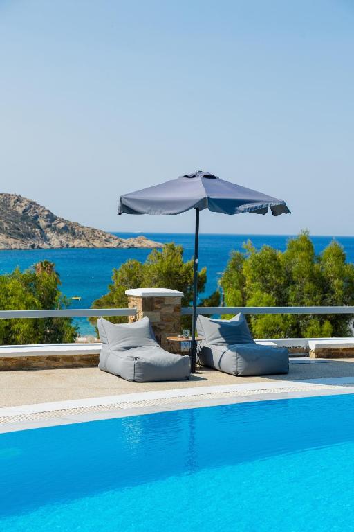 a swimming pool with an umbrella and chairs next to a swimming pool at Holidays In Ios in Mylopotas