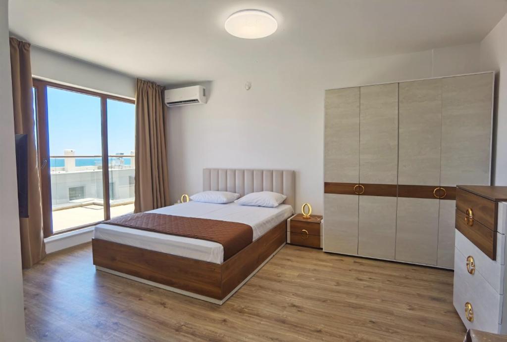 a bedroom with a bed and a large window at Cabacum Pleasure Beachfront Apartments in Varna City