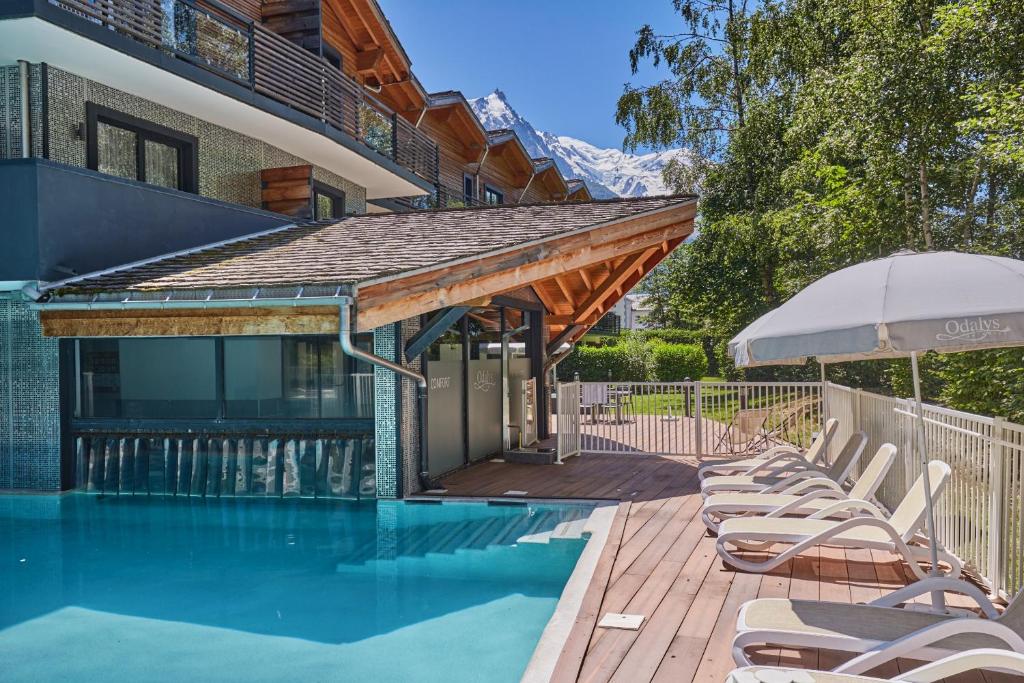 une piscine avec des chaises longues et un parasol dans l'établissement Résidence Prestige Odalys Isatis, à Chamonix-Mont-Blanc