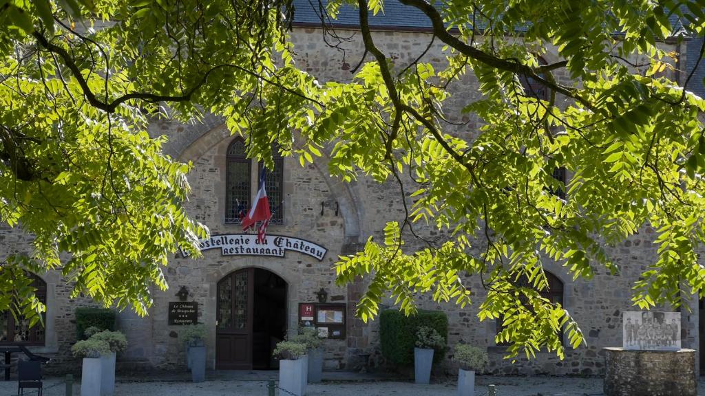 a stone building with a flag in front of it at L'Hostellerie du Château de Bricquebec in Bricquebec