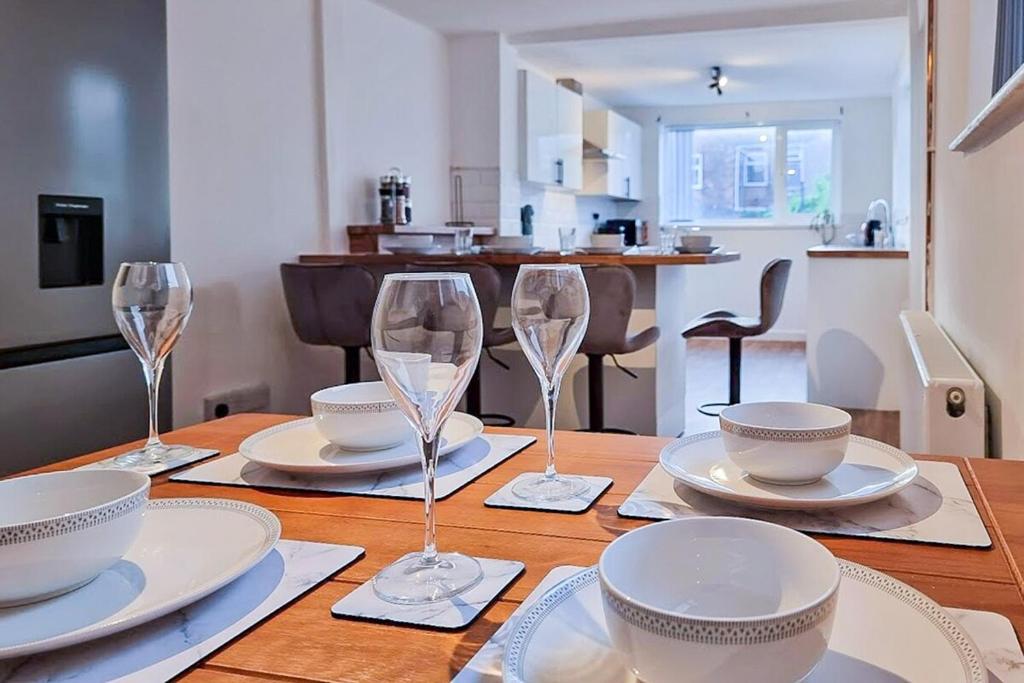 einem Holztisch mit Weingläsern und Tellern darauf in der Unterkunft Modern Comforts in Cleethorpes in Cleethorpes