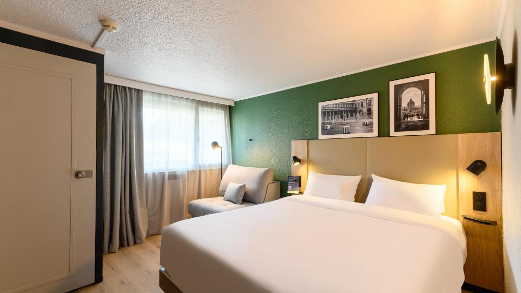 une chambre avec un lit blanc et un mur vert dans l'établissement Campanile PRIME - Montpellier Est Le Millénaire, à Montpellier