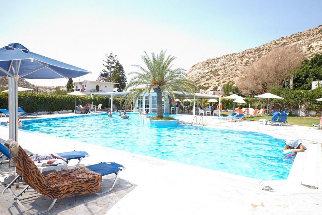 a large swimming pool with chairs and umbrellas at Elea Terra Hotel in Matala