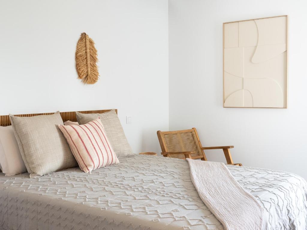 a bedroom with a bed with pink pillows and a chair at Retiro do Gerês in Geres