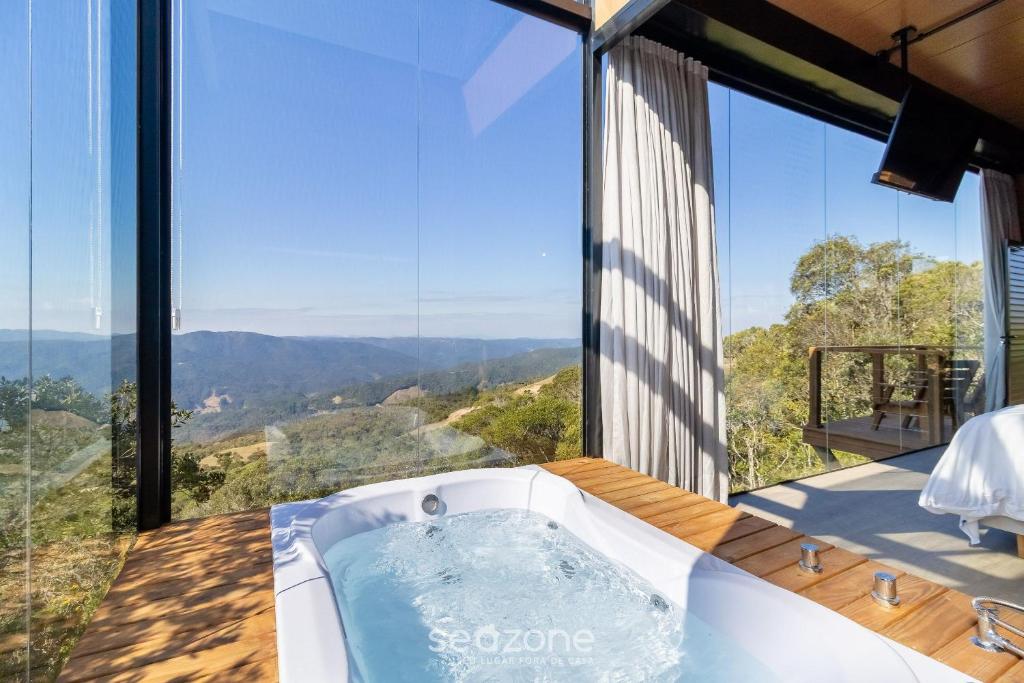 a jacuzzi tub in a room with large windows at Cabana romântica com vista na serra VST037 in São Paulo dos Pinhais