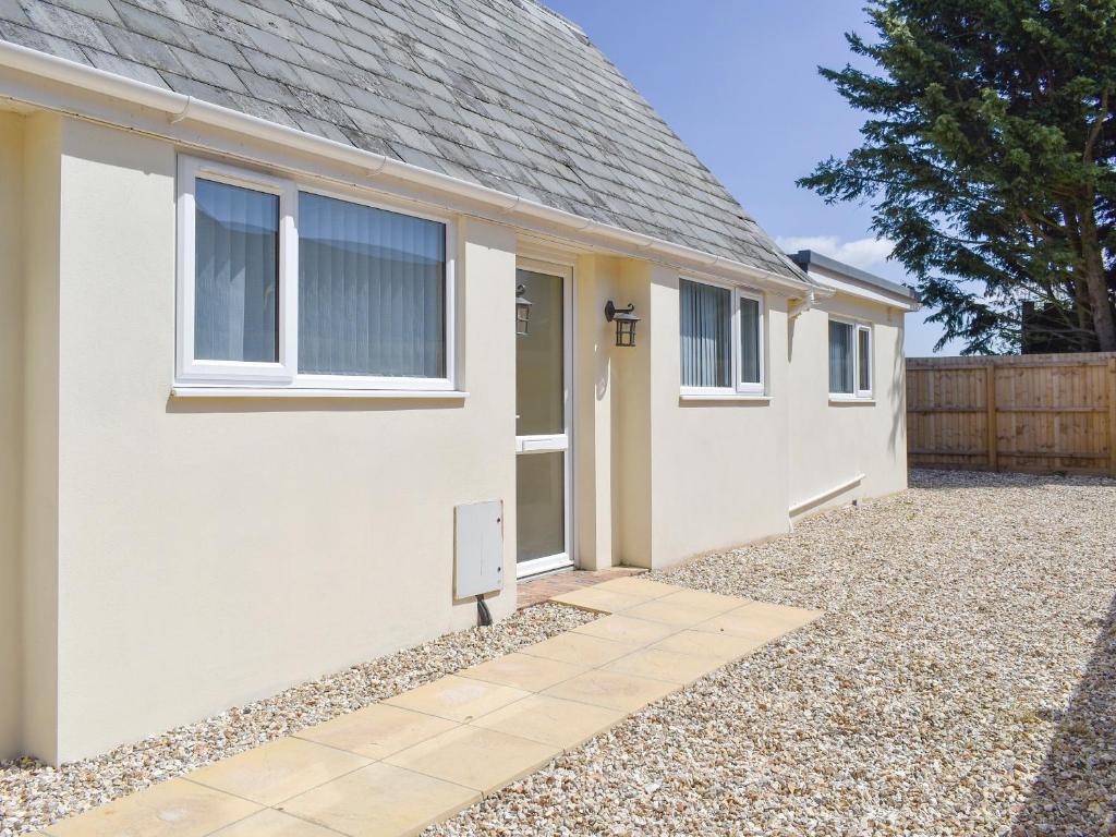 ein weißes Haus mit einer Tür und einer Kieseinfahrt in der Unterkunft Stars Cottage in Moreton