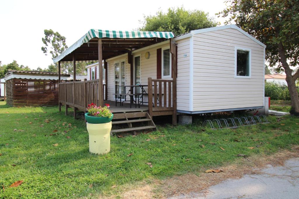 a small white house with a porch and a table at Land's Hause Bungalows par La Conciergerie Française Emplacement 11AA in Pataias