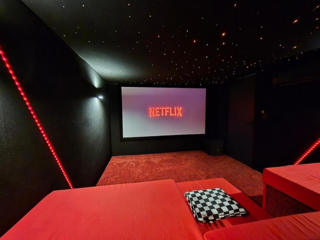 a theatre room with a red couch and a television at L'évasion Cinégame - Gîte à thème in Diebolsheim