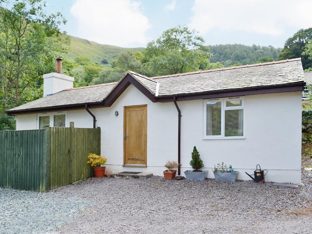 a white house with a wooden door and a fence at Minafon in Penmaen-mawr