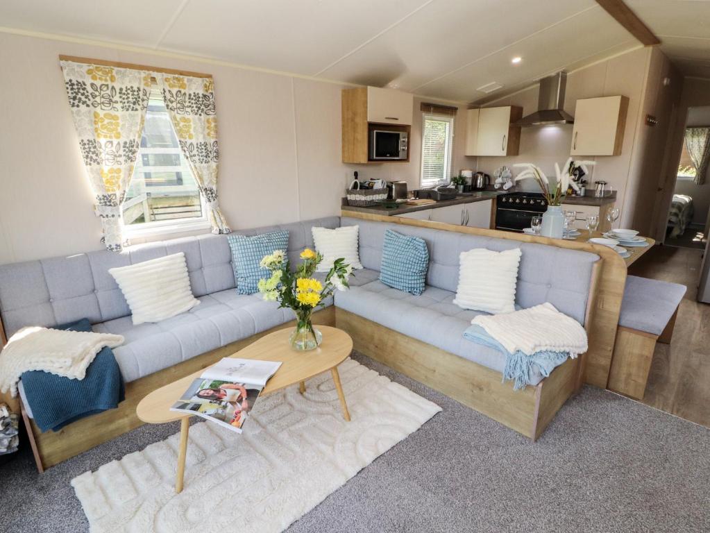 a living room with a blue couch and a kitchen at Barney's Retreat - Docker Park Farm in Carnforth