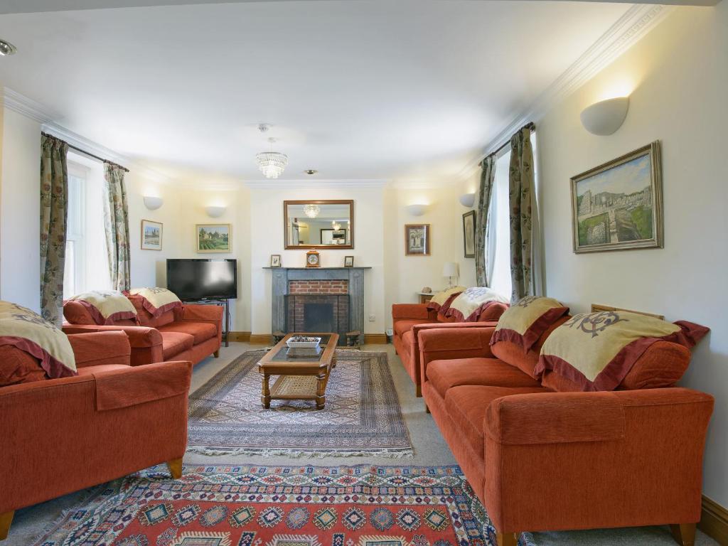 a living room with red couches and a fireplace at Fernlea in Langton Matravers