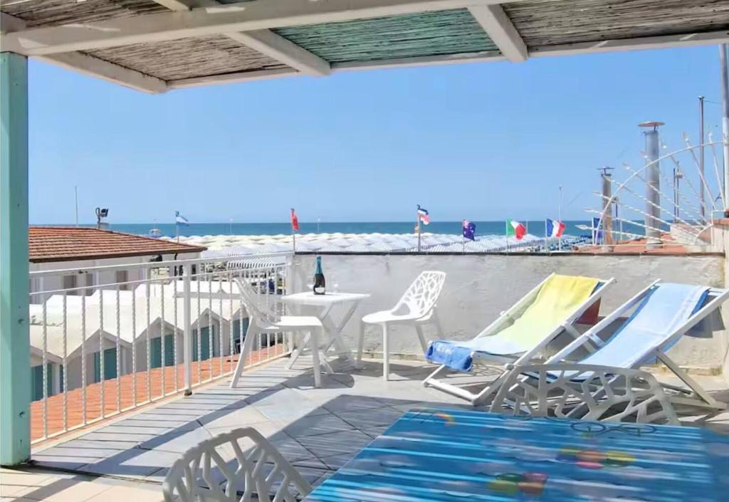 a patio with chairs and a table and the beach at Terrazza sul Mare in Lido di Camaiore