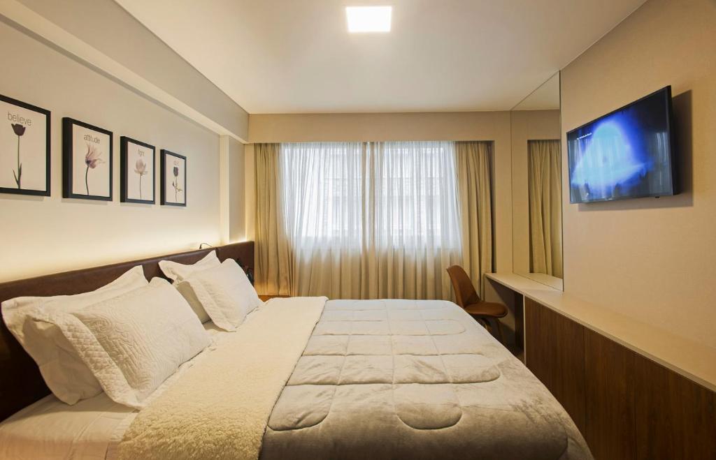 a hotel room with a bed and a flat screen tv at Vita Boulevard Gramado in Gramado