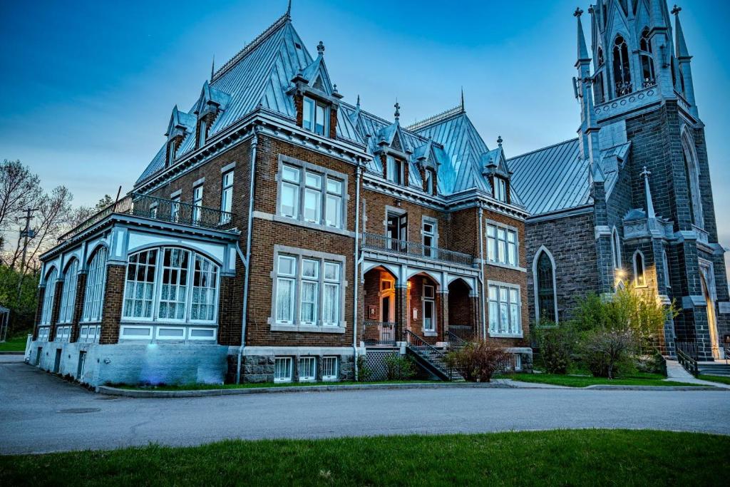 a large brick building with a clock tower at Hôtel Château Cran Chaud Chicoutimi in Saguenay