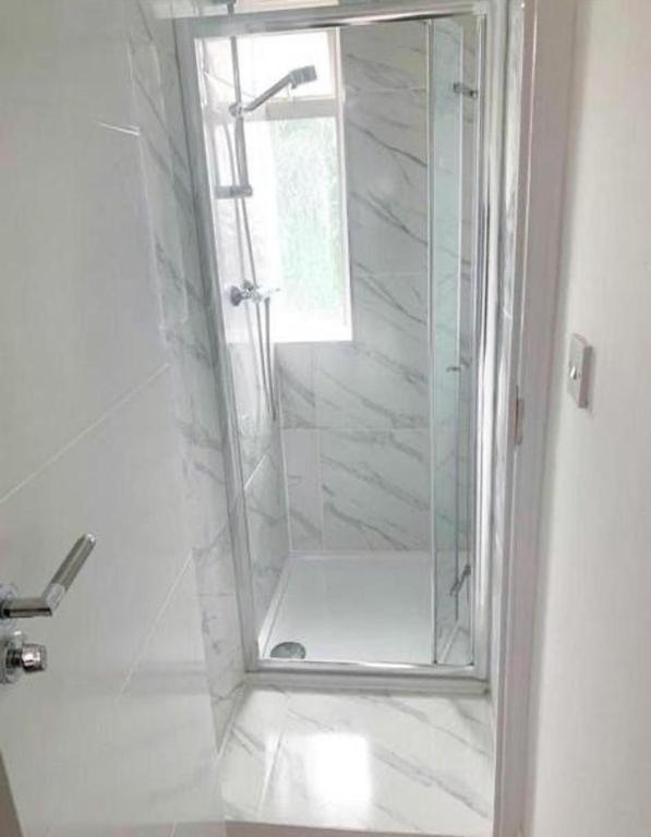 a shower with a glass door in a bathroom at Sunny Gardens 3-Bed Apartment in London in Hendon