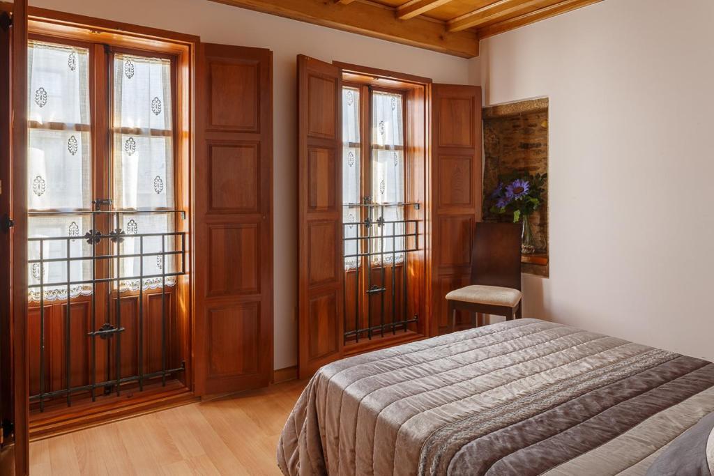a bedroom with a bed and two large windows at Apartamentos Campanas de San Juan in Santiago de Compostela