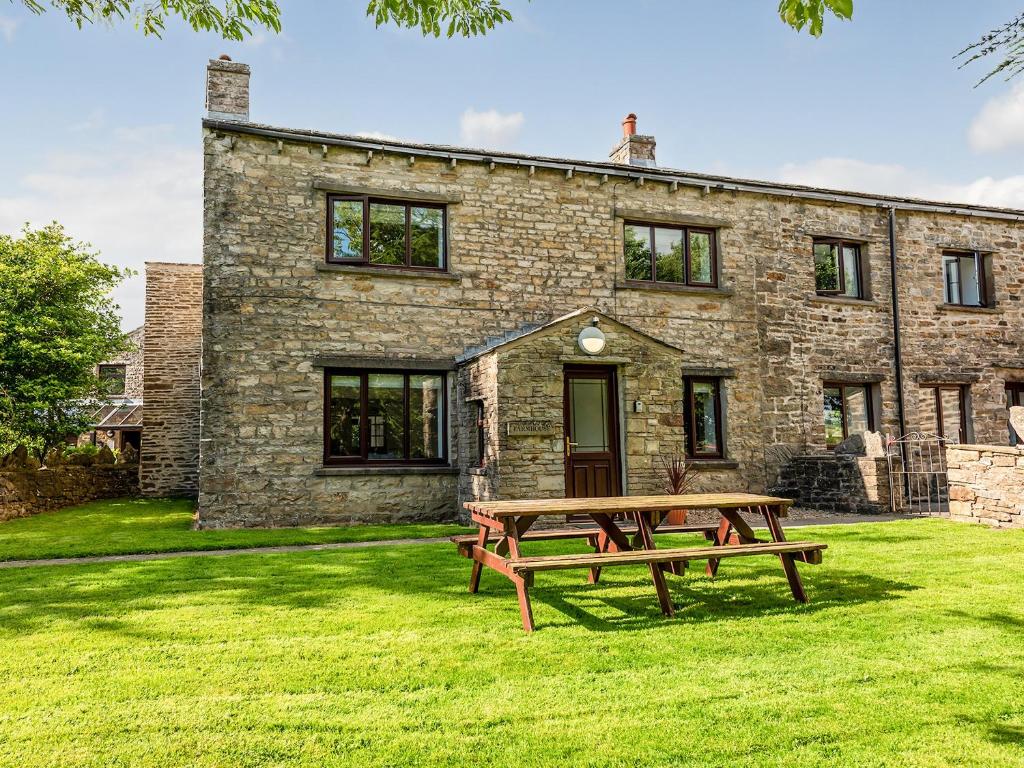una mesa de picnic frente a una casa de piedra en The Farmhouse, en Hawes
