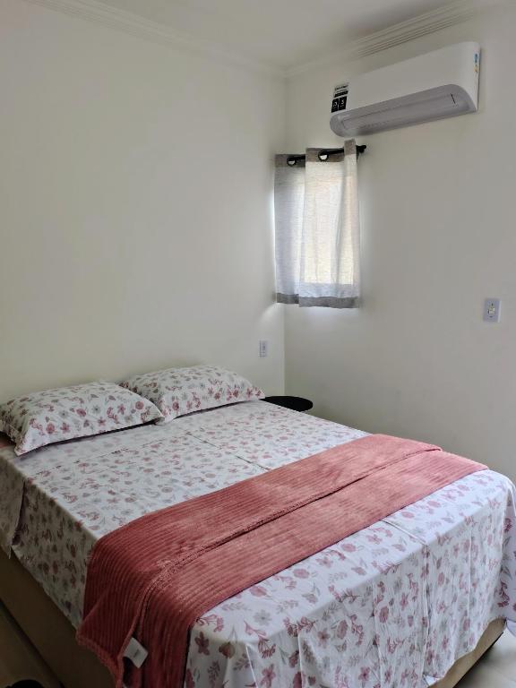 a bedroom with a bed with a red and white blanket at Suíte Da Rosa in Cachoeira Paulista