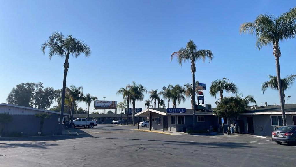 un aparcamiento con palmeras y una gasolinera en King's Inn Motel, en Kingsburg