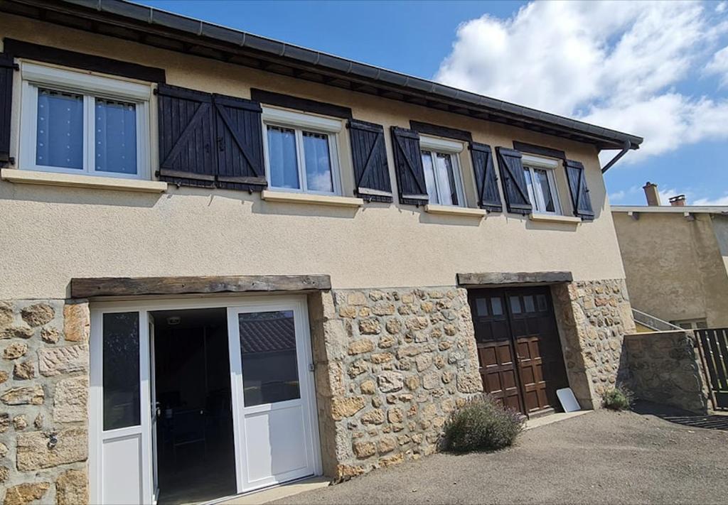 a stone house with black doors and windows at Le Cruzillou in Saint-Jean-Soleymieux