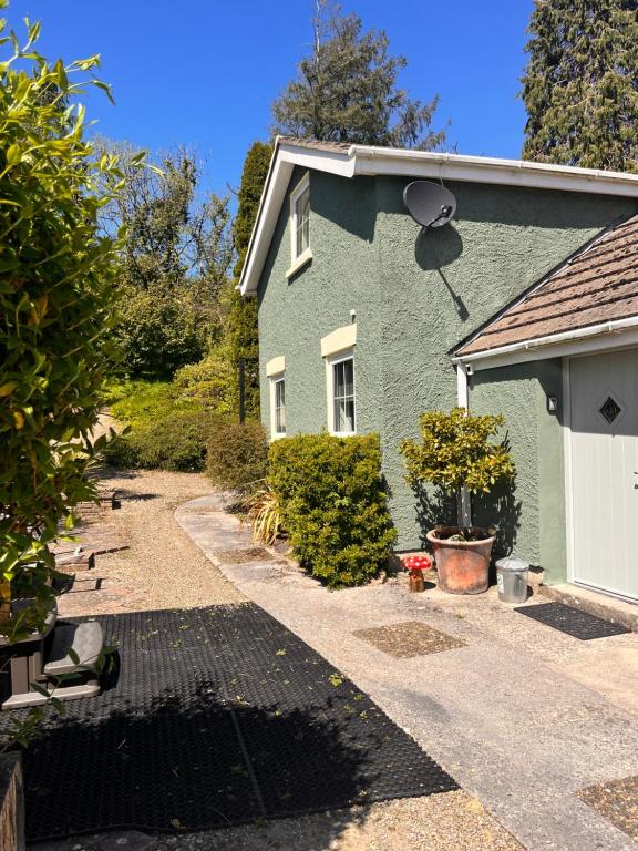 una casa verde con un vialetto davanti di Sparrows Nest Holiday Cottage ad Amroth
