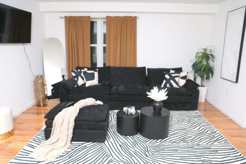 a living room with a black couch and a rug at Modern Minimalist Lux Paradise in Newark