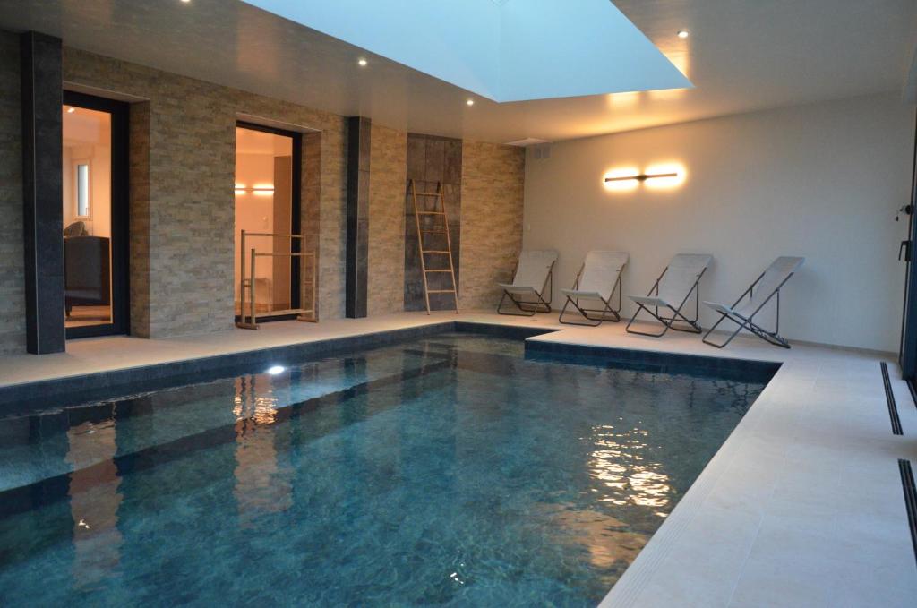 une piscine avec quatre chaises dans un bâtiment dans l'établissement Maison bord de mer - Baie de Douarnenez - Piscine couverte, à PloÃ©ven
