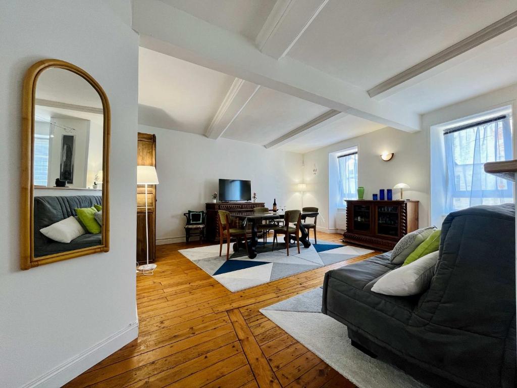 a living room with a black couch and a mirror at The Duplex des Flots In the heart of Grandcamp just steps from the beach in Grandcamp-Maisy
