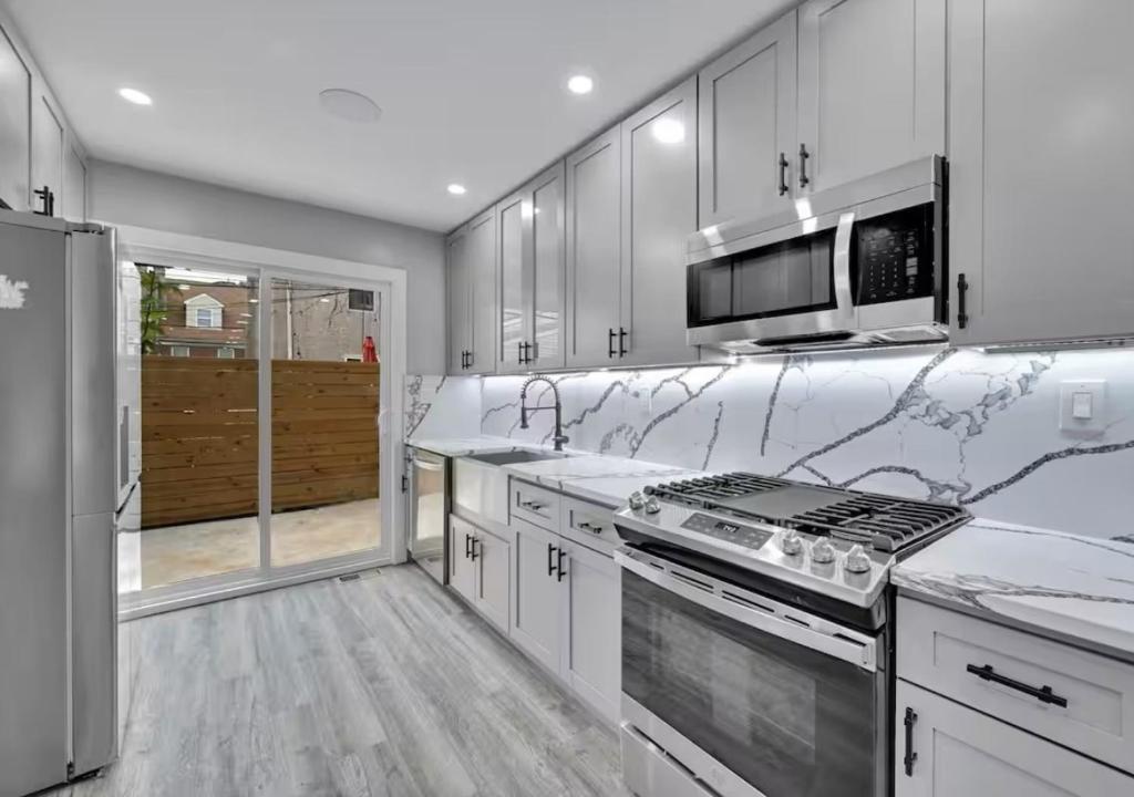 une cuisine avec des armoires blanches et un four à plaques de cuisson dans l'établissement 5BR Home near City Center, Live! Casino, Hot Tub with City View, à Philadelphie