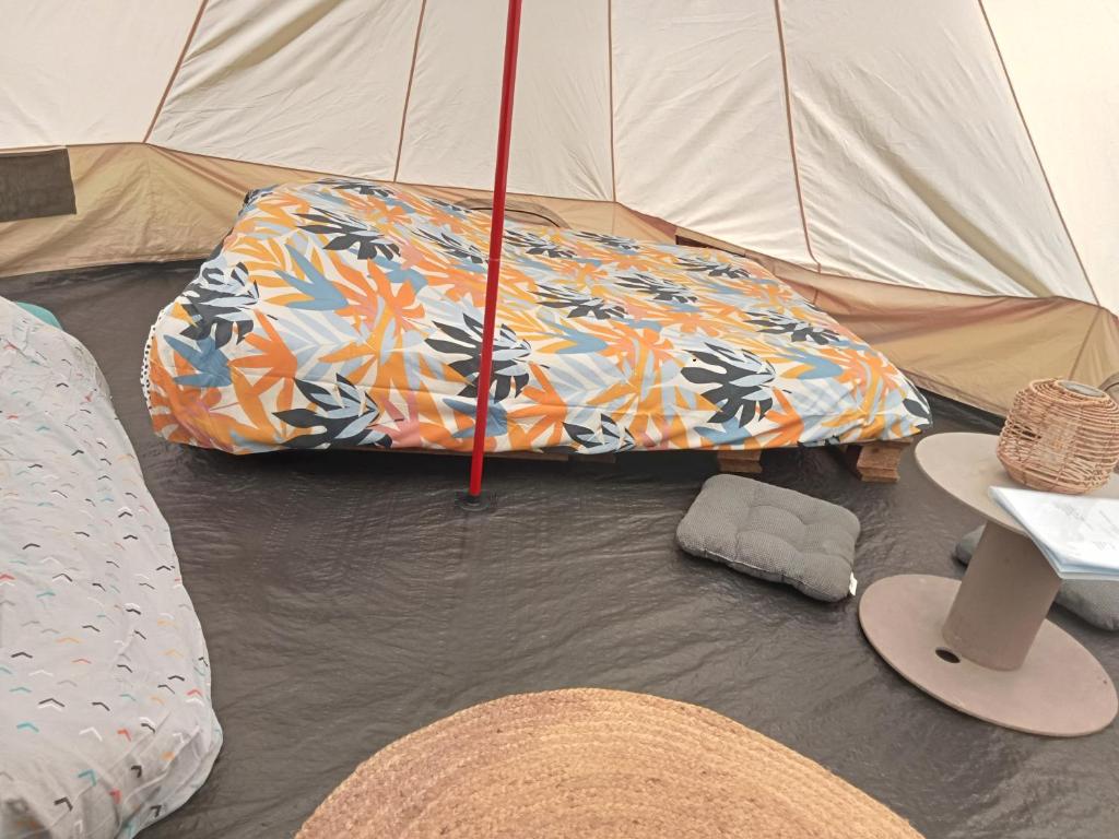 une tente avec un matelas et un parasol au sol dans l'établissement tente nature, à Plouray