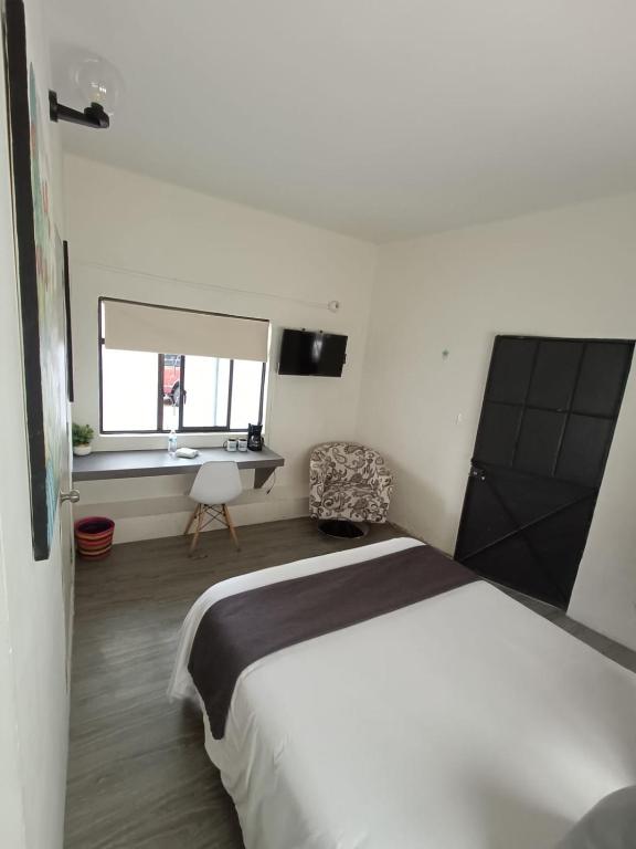a bedroom with a bed and a desk and a window at HERMILA Tlalpan in Mexico City