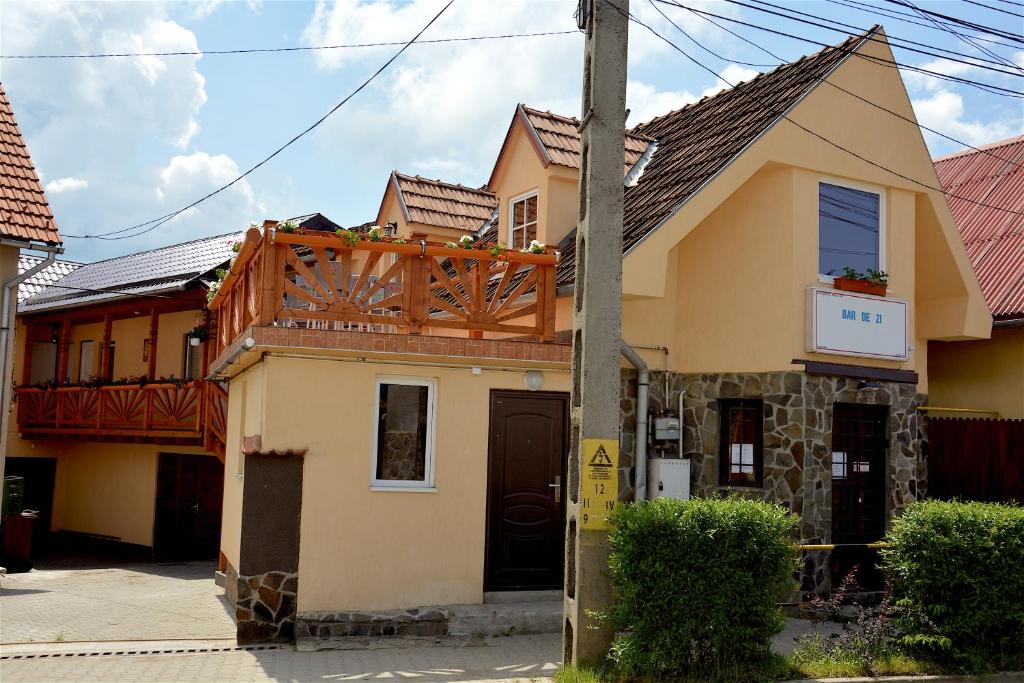 a yellow house with a wooden roof at Tornácos Vendégház in Vlăhiţa