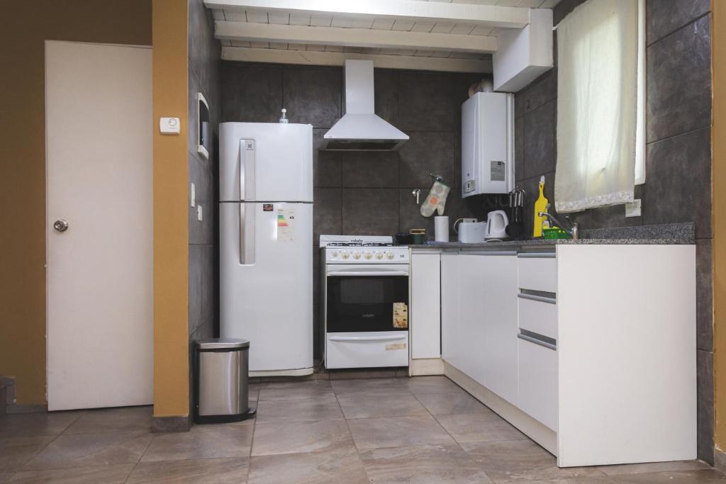 une cuisine avec des appareils électroménagers blancs et des armoires blanches dans l'établissement Apart BANDURRIAS I - a 200ms del Lago Lacar, à San Martín de los Andes