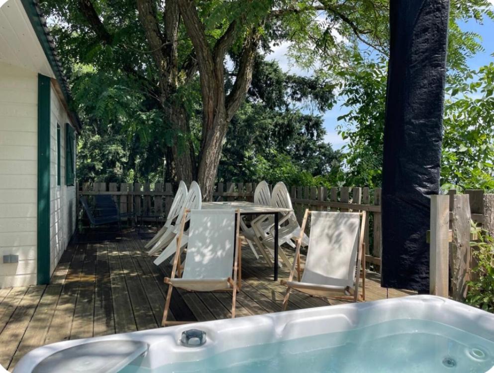 patio z krzesłami, stołem i wanną w obiekcie La foret des hérissons w mieście Longessaigne