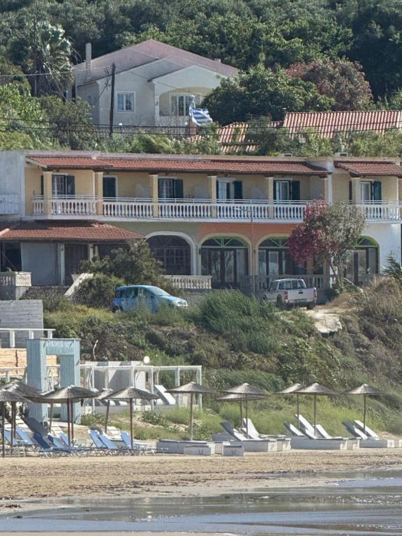 una grande casa sulla spiaggia con sedie e ombrelloni di SeasoundStudios ad Agios Stefanos