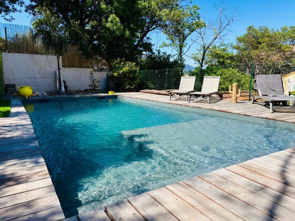 une piscine avec des chaises et une terrasse en bois dans l'établissement LA VILLA, au Pradet