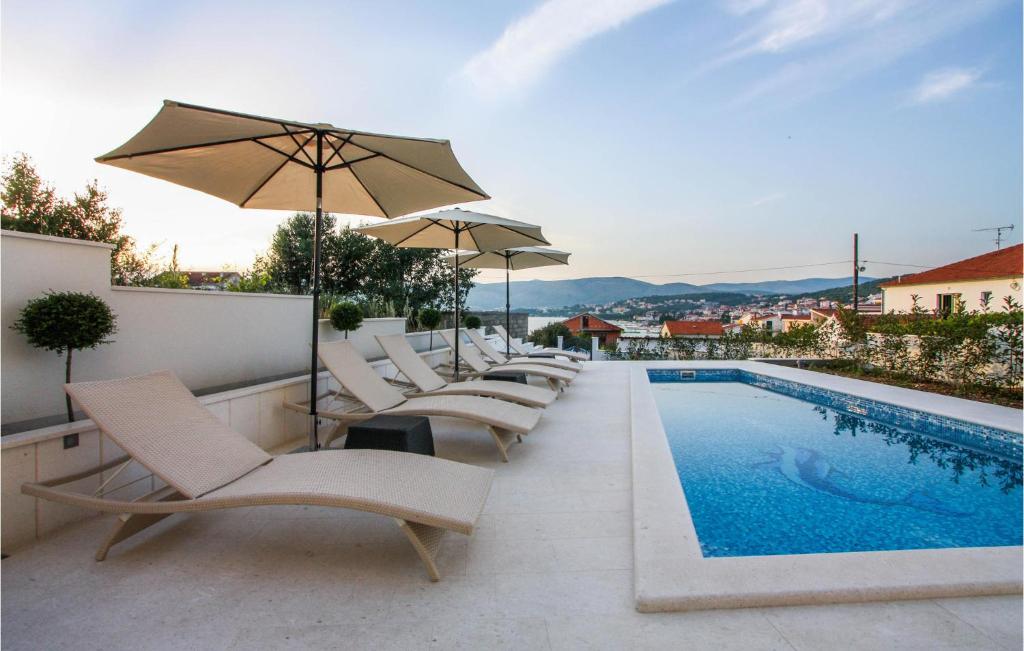 a swimming pool with lounge chairs and an umbrella at Amazing Home In Okrug Gornji in Trogir