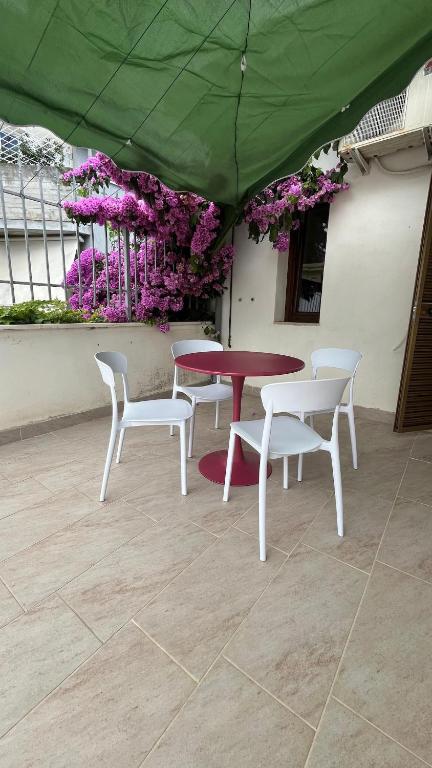 a table and chairs with a green umbrella and purple flowers at Casamare in Roseto degli Abruzzi