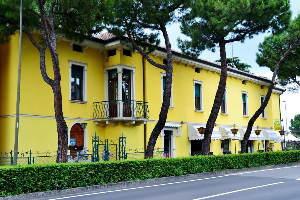 代森扎諾－德爾加達的住宿－South Garda Suites，街道前方有树木的黄色房子