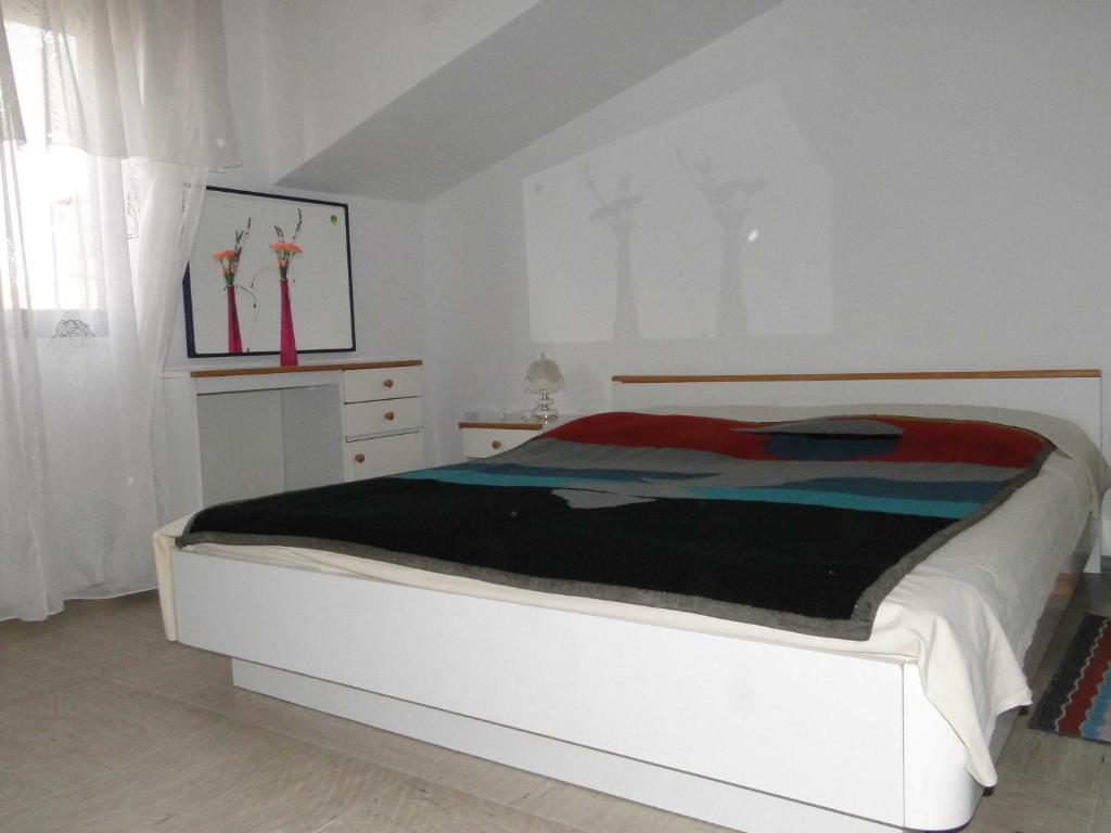 a white bedroom with a bed with a black blanket at Apartments Majic in Trogir