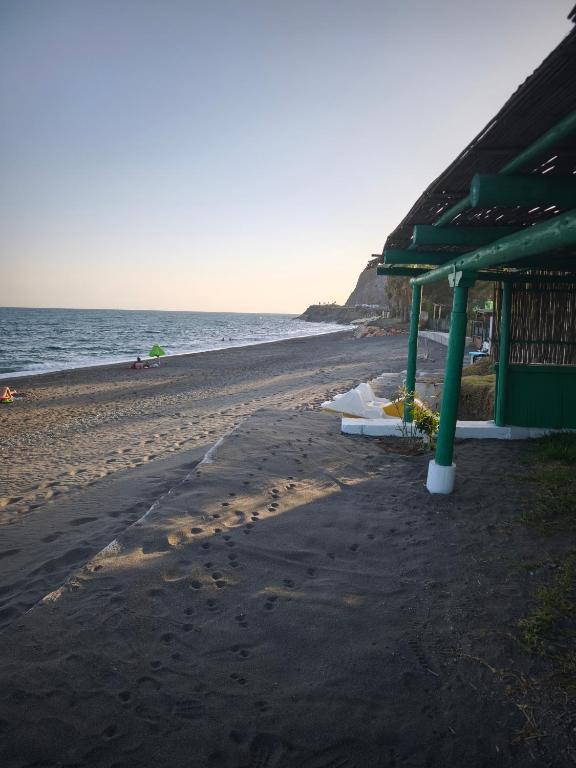 a beach with a green building and the ocean at Valle Niza, N 340, 21, Villa Playa in Vélez-Málaga