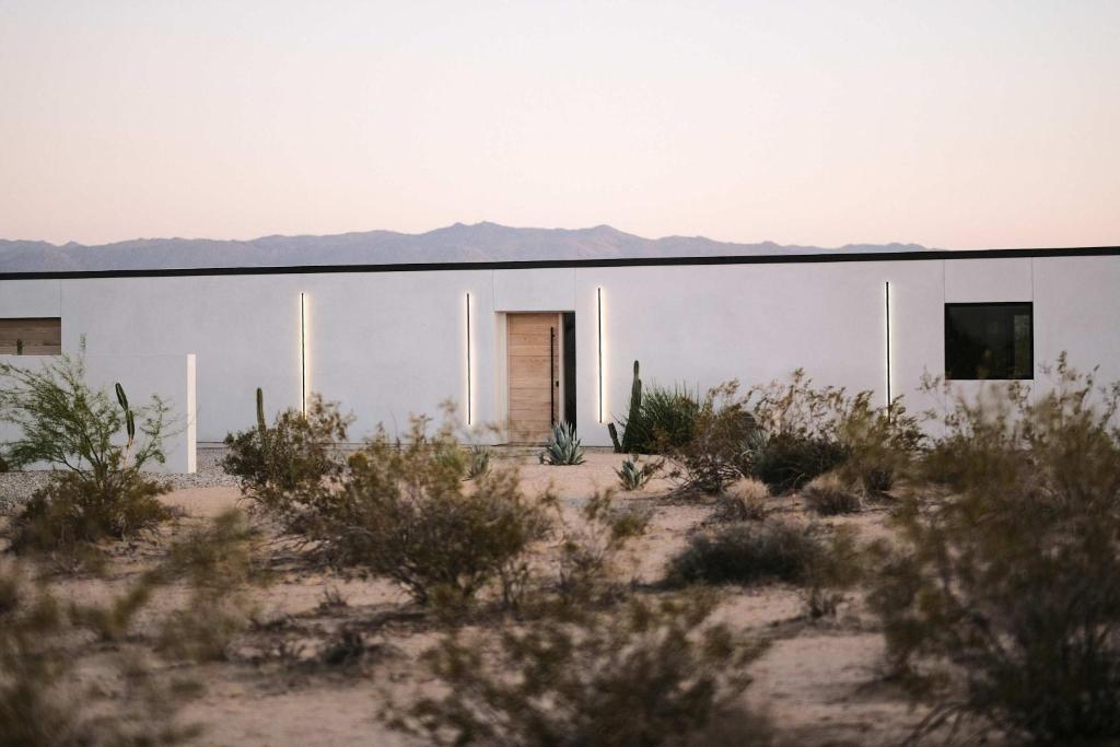 un edificio blanco en el desierto con montañas en el fondo en SkyDweller - Joshua Tree Modern, en Joshua Tree