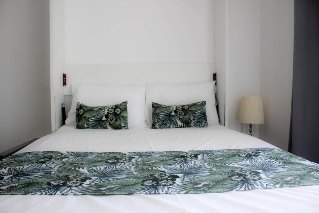 a bedroom with a large white bed with green pillows at stuDio 57 II in Alexandroupoli